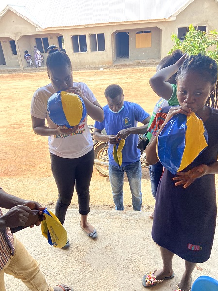 Ghanaian children blowing up blue and gold Drexel University beach balls.